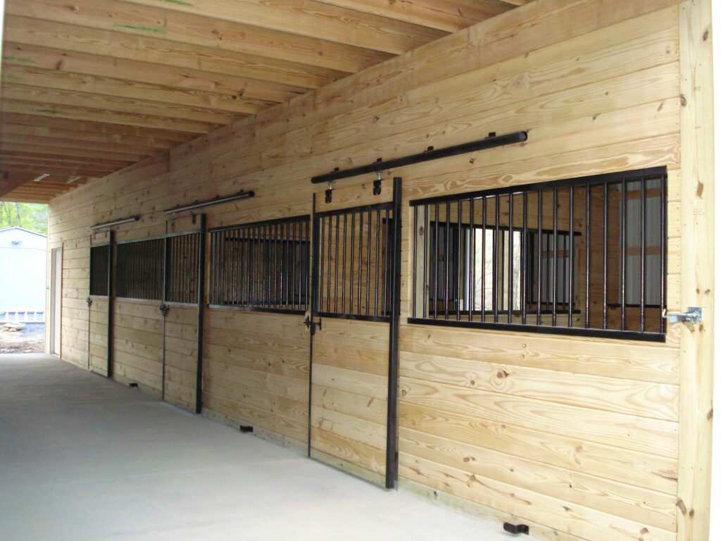 The inside of a horse barn with stalls and metal doors.